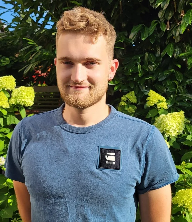 Der Leiter des Posaunenchors, Jabbo Ubbens, in der Sonne vor einem Strauch