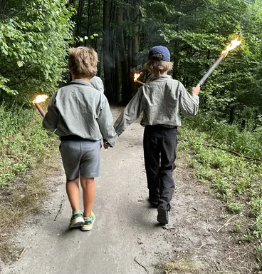 2 junge Pfadfinder mit Fackeln im Wald